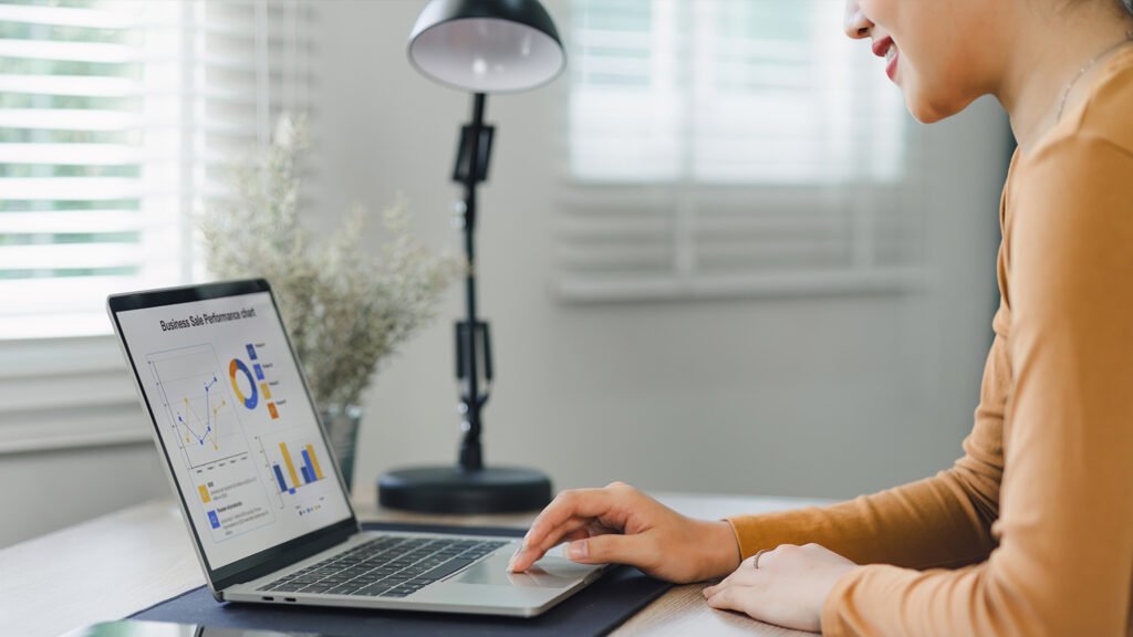 A lady sitting on desk and Doing task on laptop.
