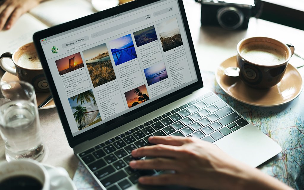A person's hands are shown typing on a laptop displaying a visually rich website, possibly illustrating content marketing.