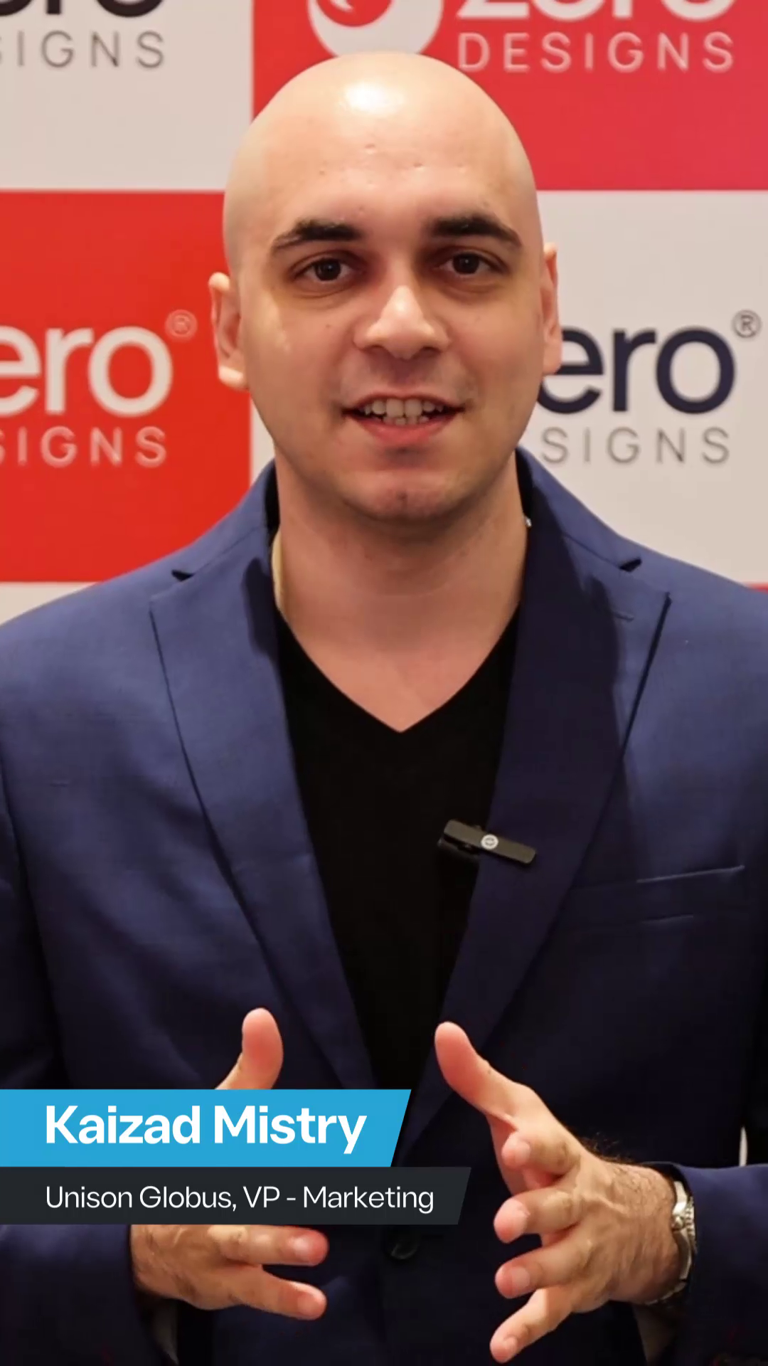 Kaizad Mistry, VP of Marketing at Unison Globus, speaking in front of a Zero Designs backdrop, wearing a blue blazer and gesturing with his hands.