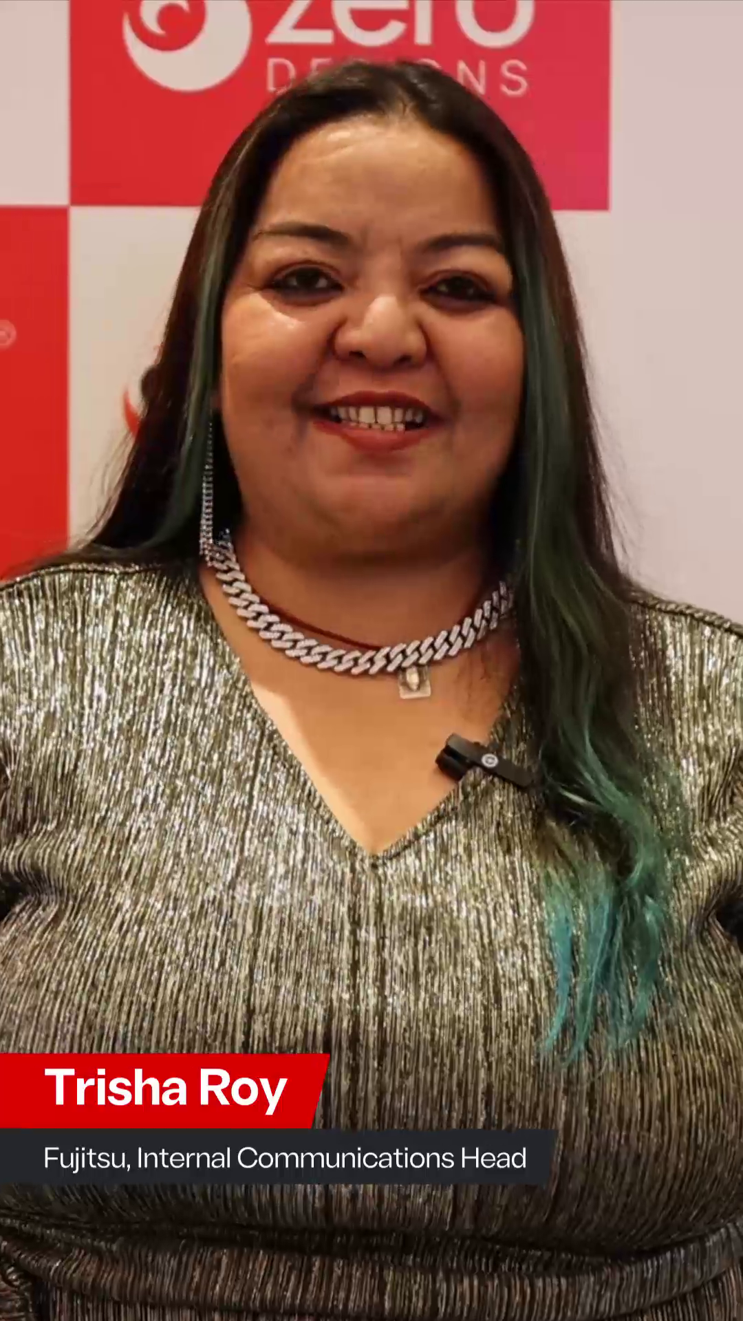 Trisha Roy, Internal Communications Head at Fujitsu, smiling in front of a Zero Designs backdrop. She is wearing a glittery silver dress and a silver chain necklace, with a text overlay displaying her name and title.